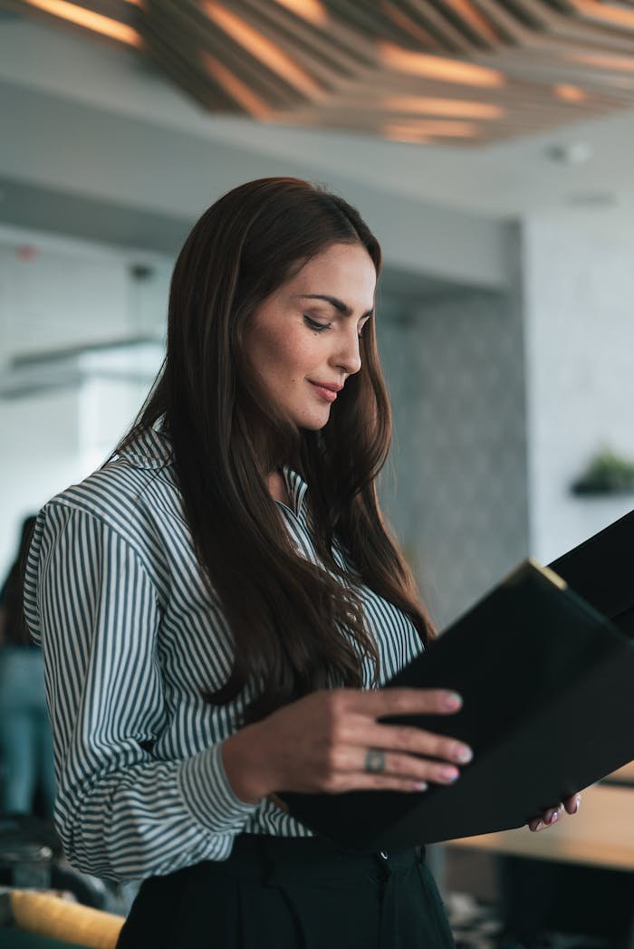 Businesswoman reading documents in a modern office setting.