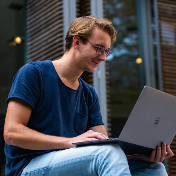 A young man sitting outdoors in Leiden, Netherlands, working on a laptop.