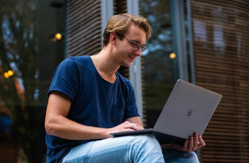 A young man sitting outdoors in Leiden, Netherlands, working on a laptop.