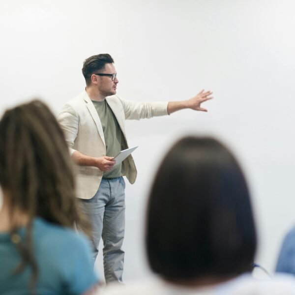 A man in a blazer gives a presentation to a captivated audience in a lecture setting.