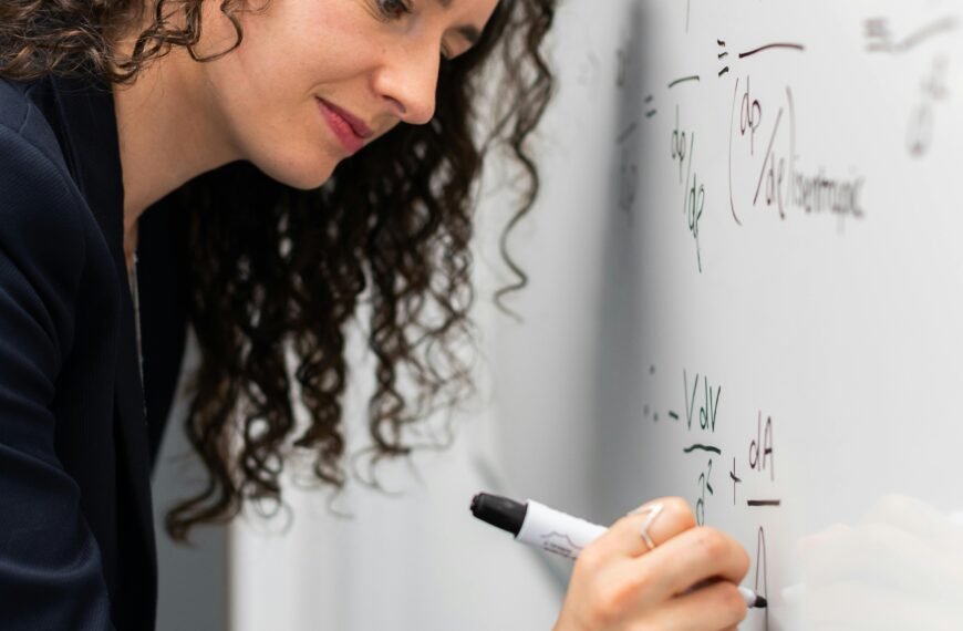 Female engineer solving equations on whiteboard with focus and precision.