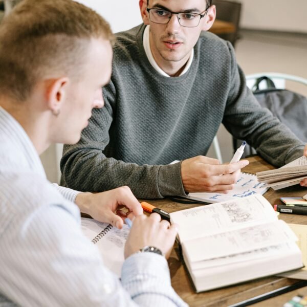 Two young men studying together at a table with books and notes.