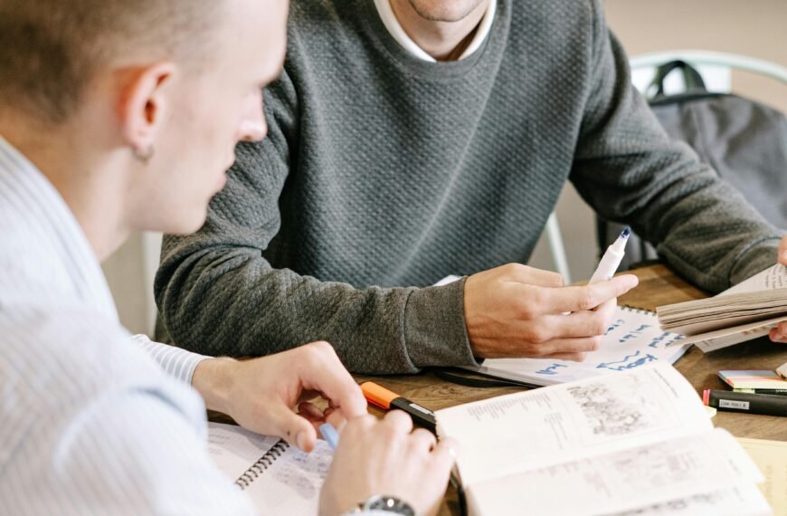 Two young men studying together at a table with books and notes.