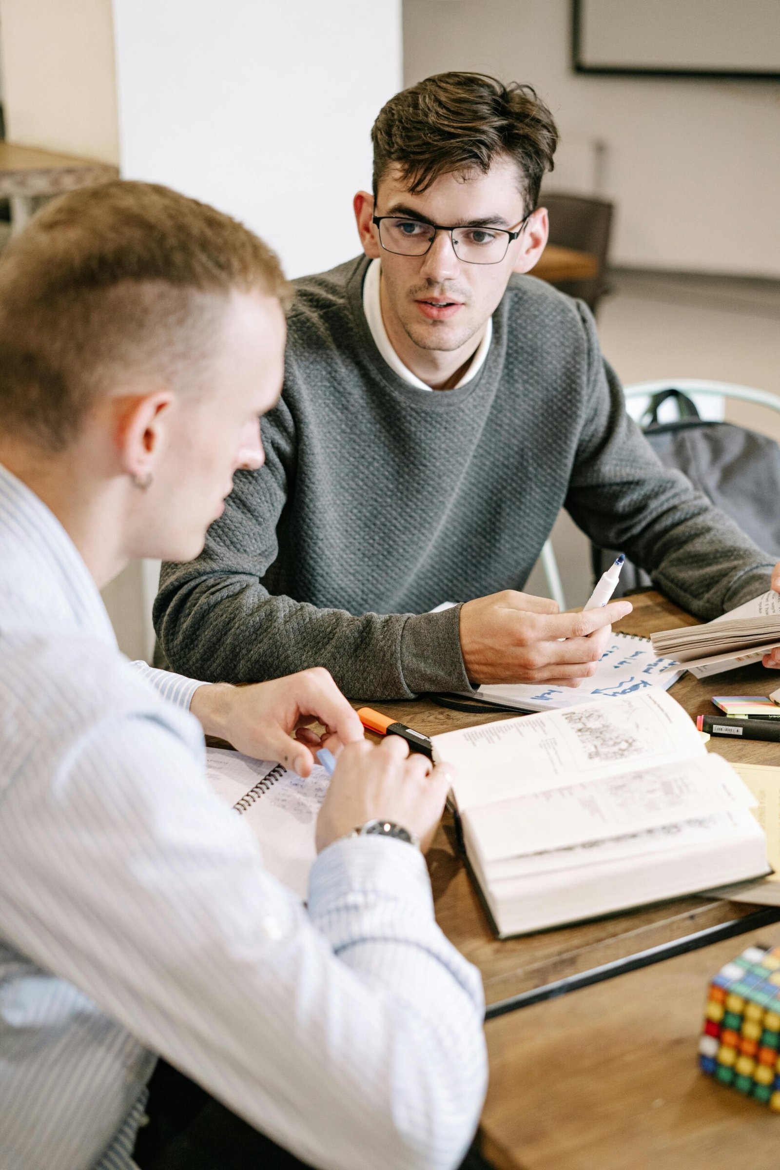 Two young men studying together at a table with books and notes.