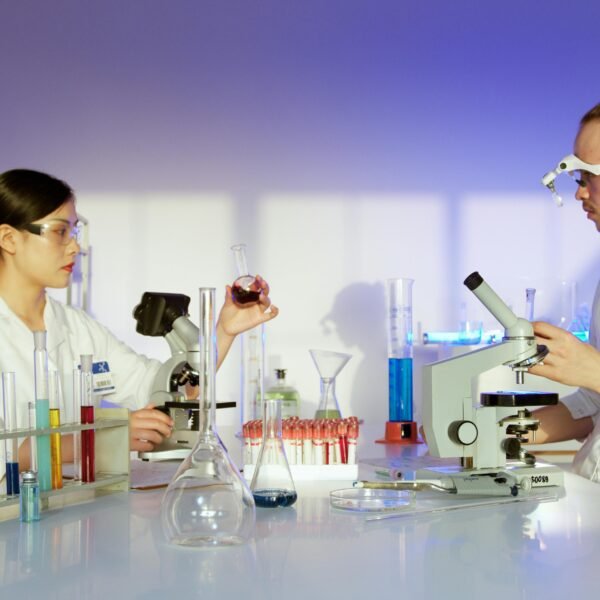 Two scientists working in a well-equipped laboratory conducting chemical research and experiments.