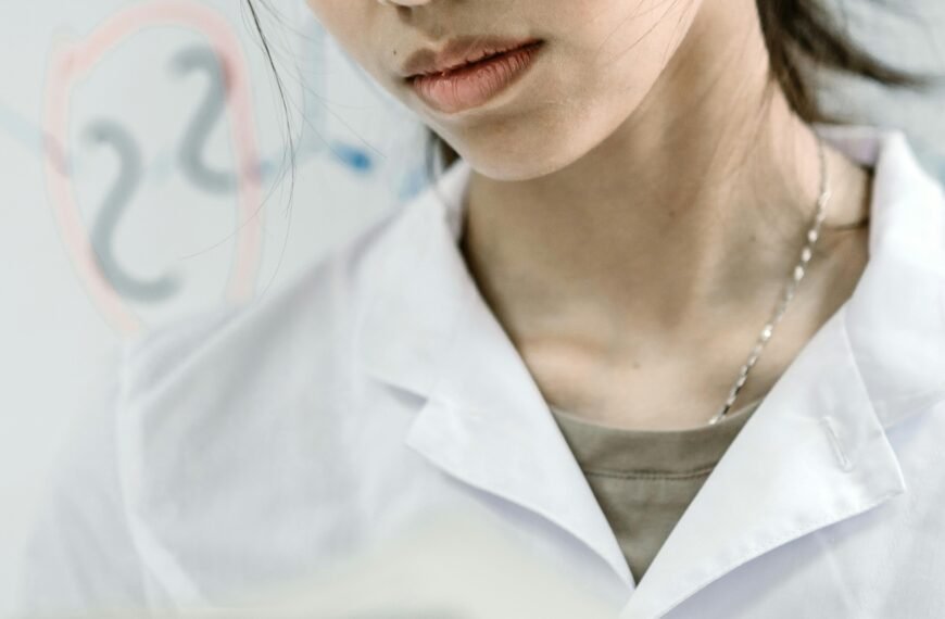 Asian female scientist in lab coat reading a book, experimenting in a laboratory setting.