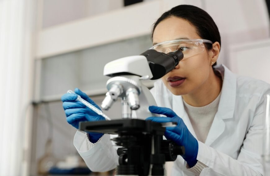 A female scientist examines samples using a microscope in a laboratory setting.