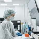 Scientist in lab coat and mask analyzing samples in a modern lab.