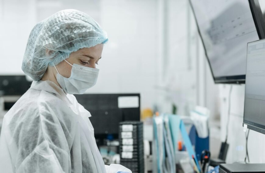 Scientist in lab coat and mask analyzing samples in a modern lab.