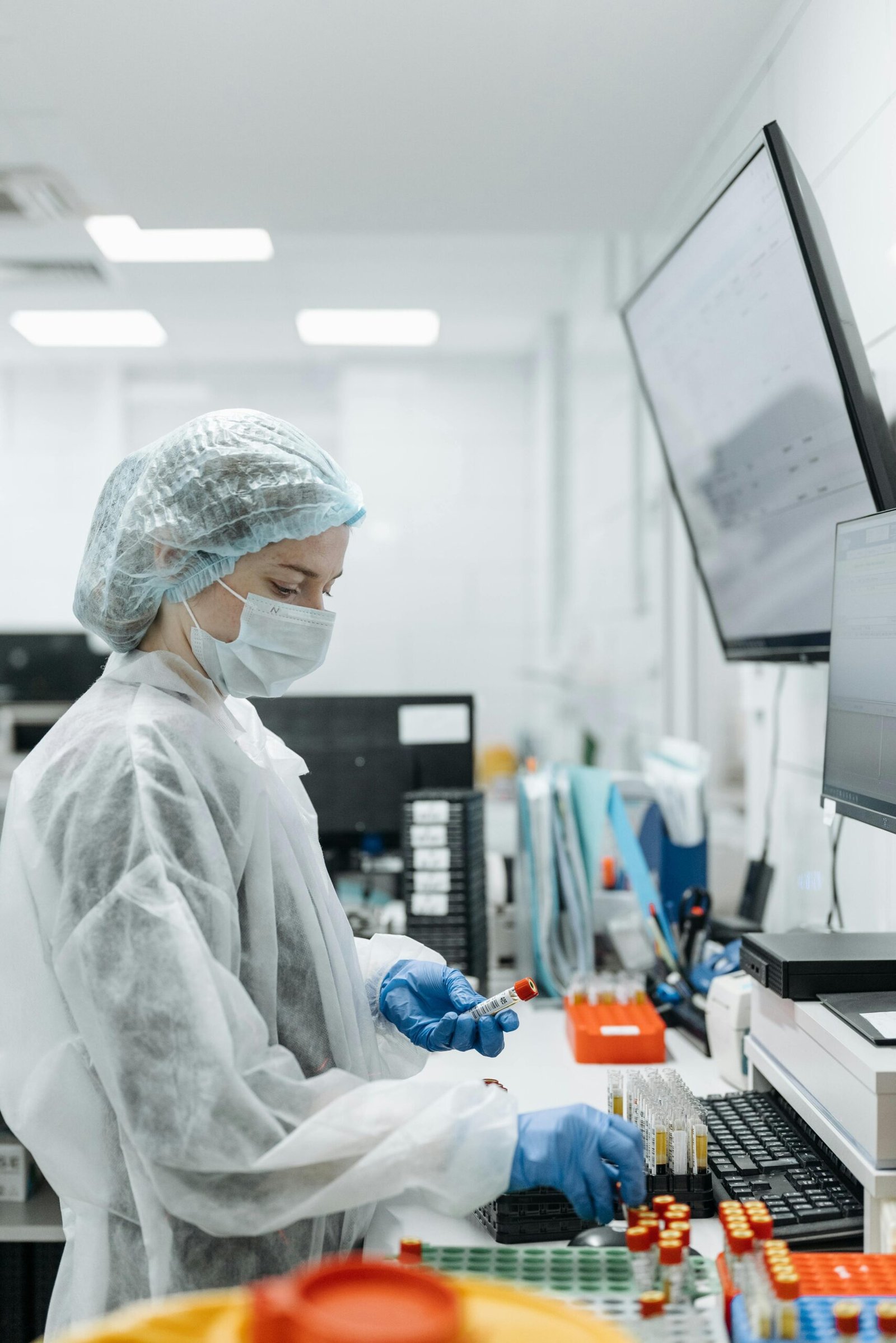 Scientist in lab coat and mask analyzing samples in a modern lab.