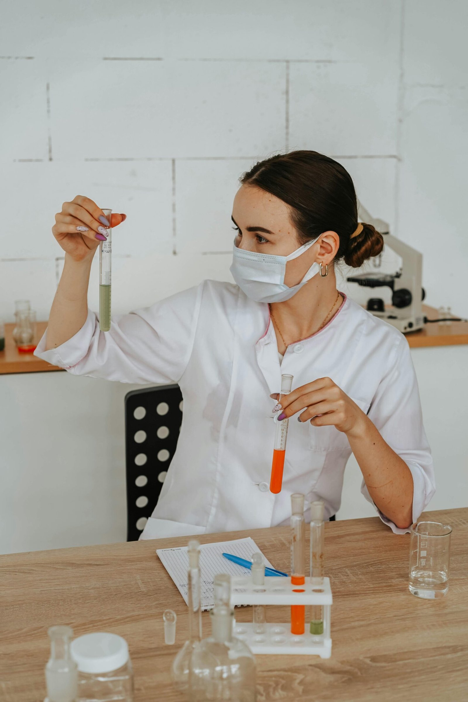 A female scientist carefully examines test tubes in a laboratory setting, showcasing scientific research and discovery.