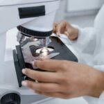 Scientist in laboratory using a microscope for detailed sample analysis.